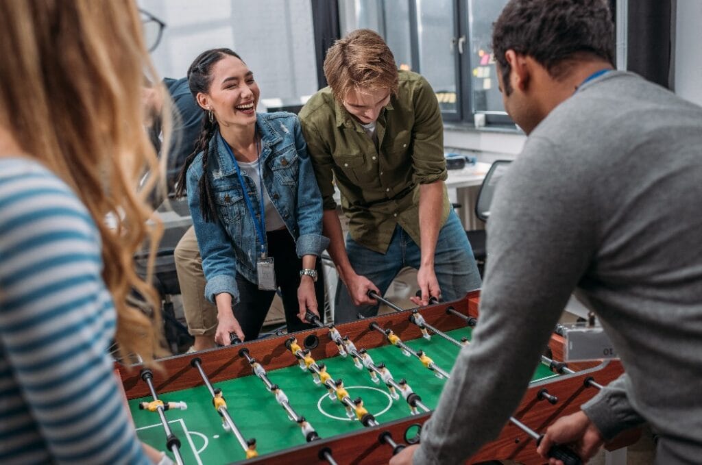 glückliche multikulturelle Menschen beim Tischfußballspiel im Modern Off